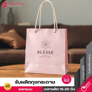 รับผลิตถุงกระดาษ สีชมพูพาสเทล ดีไซน์แนวมินิมอล พร้อมพิมพ์โลโก้ จัดโชว์อยู่บนโต๊ะไม้สีน้ำตาล