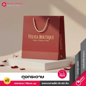 ถุงกระดาษ VELVIA BOUTIQUE สีแดงเบอร์กันดี พิมพ์โลโก้สีทอง หูหิ้วเชือกสีขาว วางบนแท่นโชว์